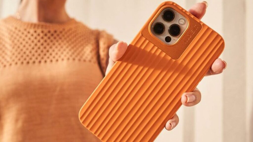 Orange nudient mobile phone case with woman holding it blurry in the background wearing an orange knitted top